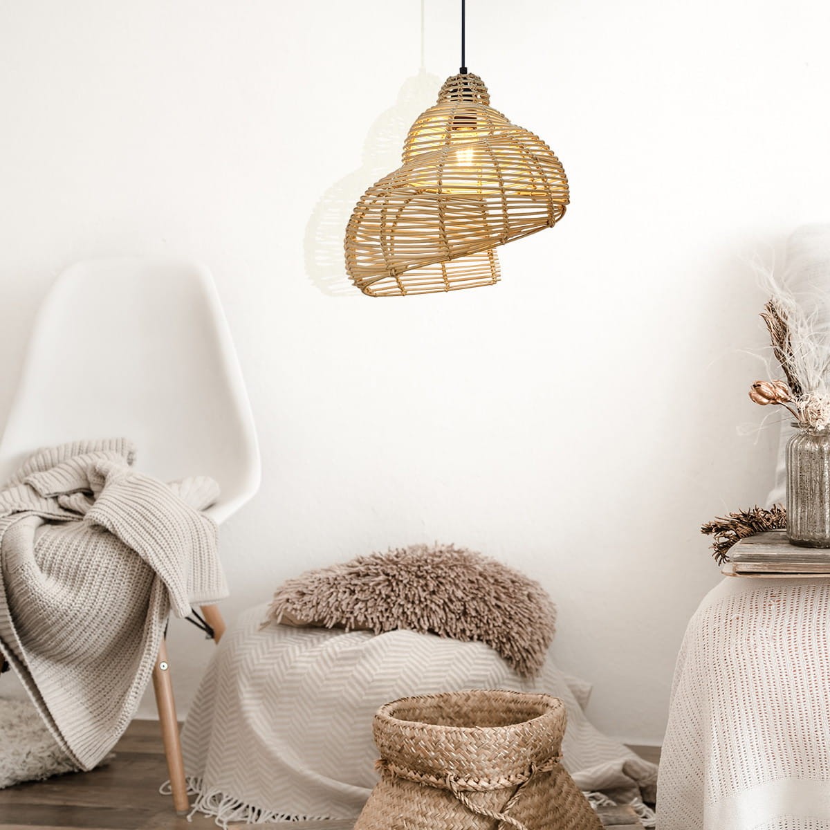 Lampa wisząca Shella D40 o kształcie serca, wykonana z rattanowych pasków w kolorze naturalnym, zawieszona na czarnym przewodzie. W tle widoczna biała krzesło i elementy tekstylne w neutralnych odcieniach.