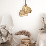 Lampa wisząca Shella D40 o kształcie serca, wykonana z rattanowych pasków w kolorze naturalnym, zawieszona na czarnym przewodzie. W tle widoczna biała krzesło i elementy tekstylne w neutralnych odcieniach.