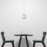 Lampa wisząca LED Brillant LP-3303/1P GD o okrągłym kształcie, wykonana ze szkła z delikatnymi żłobieniami, zawieszona na białym kablu. Złoty detal u góry. Widoczna w minimalistycznym wnętrzu z czarnym stołem i krzesłami.