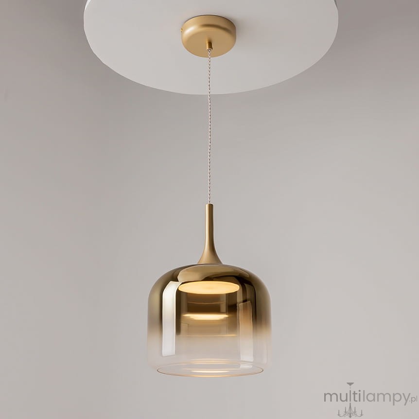 Lampa wisząca Spirito LED 12W w kolorze złotym, o zaokrąglonym kształcie klosza z transparentnym wykończeniem. Zawieszona na cienkim przewodzie, montowana do sufitu. Elegancki design idealny do nowoczesnych wnętrz.