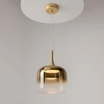 Lampa wisząca Spirito LED 12W w kolorze złotym, o zaokrąglonym kształcie klosza z transparentnym wykończeniem. Zawieszona na cienkim przewodzie, montowana do sufitu. Elegancki design idealny do nowoczesnych wnętrz.