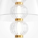 Lampa stołowa LED Amulet 10W w złotym kolorze, z przezroczystymi, falistymi elementami szklanymi, umieszczona na przezroczystym szkle. Widok z góry, ukazujący detale i strukturę lampy.