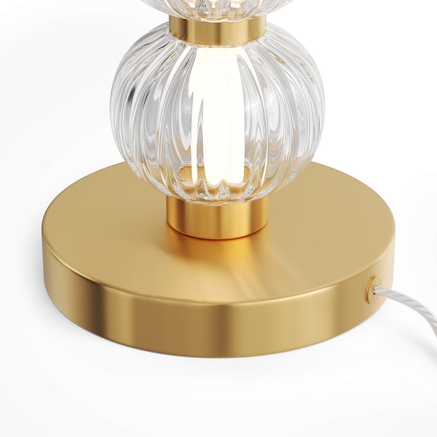 Amulet lampa stołowa LED 10W w złotej oprawie z przezroczystym kloszem o żłobionej fakturze, z okrągłą podstawą. Widoczny kabel zasilający po prawej stronie. Kąt ujęcia zbliżony na detal.