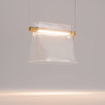 Lampa wisząca LED Cabaret o mocy 8W, wykonana z przezroczystego materiału z mosiężnym detalem. Ujęcie z przodu, lampa wisi na cienkim przewodzie. Oświetlenie umieszczone w górnej części klosza, nadające nowoczesny wygląd.