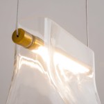 Lampa wisząca Cabaret z mosiężnym detalem, w kształcie falistego, przezroczystego klosza. Widoczna LED-owa żarówka o mocy 8W, zawieszona na cienkim przewodzie. Klosz ukazuje efektowną grę światła.