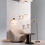 Wisząca lampa LED Cabaret o mocy 8W w kolorze mosiądzu, z przezroczystym kloszem, zawieszona na cienkim przewodzie. W tle widoczna aksamitna, jasna sofa oraz stolik, na którym rzucają się cienie.