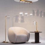 Lampa stołowa LED Cabaret o mocy 8W, wykonana z mosiądzu, z przezroczystym kloszem. Ustawiona obok okrągłego stolika i wygodnego fotela w jasnych odcieniach, na neutralnym tle.