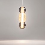 Lampa wisząca Drop 1xLED/16W w kolorze chromu, składająca się z trzech elementów: dwóch szklanych kul w odcieniach czerni i złotej, oraz środkowego, teksturowanego, przezroczystego klosza. Zawieszona na białym przewodzie w minimalistycznym otoczeniu.
