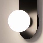 Kinkiet Bao 1xG9 w kolorze czarnym, z okrągłą, białą żarówką. Montaż ścienny, widoczny z boku. Wykonanie z matowego metalu, minimalistyczny design, idealny do nowoczesnych wnętrz. Tło jasne, podkreślające formę lampy.