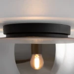 Czarna lampa sufitowa Glassy z dymionym kloszem, z widoczną żarówką E27. Ujęcie z bliska, pokazujące detal mocowania i kształt klosza, który odbija światło. Produkt zamontowany na gładkim, jasnym suficie.