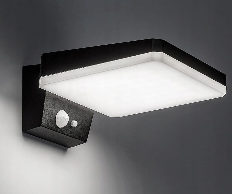 Sonda S LED kinkiet elewacyjny solarny w kolorze czarnym, z prostokątną, białą kloszem i czujnikiem ruchu oraz zmierzchu. Montowany na ścianie, widok z boku. Detal czujnika w dolnej części obudowy.