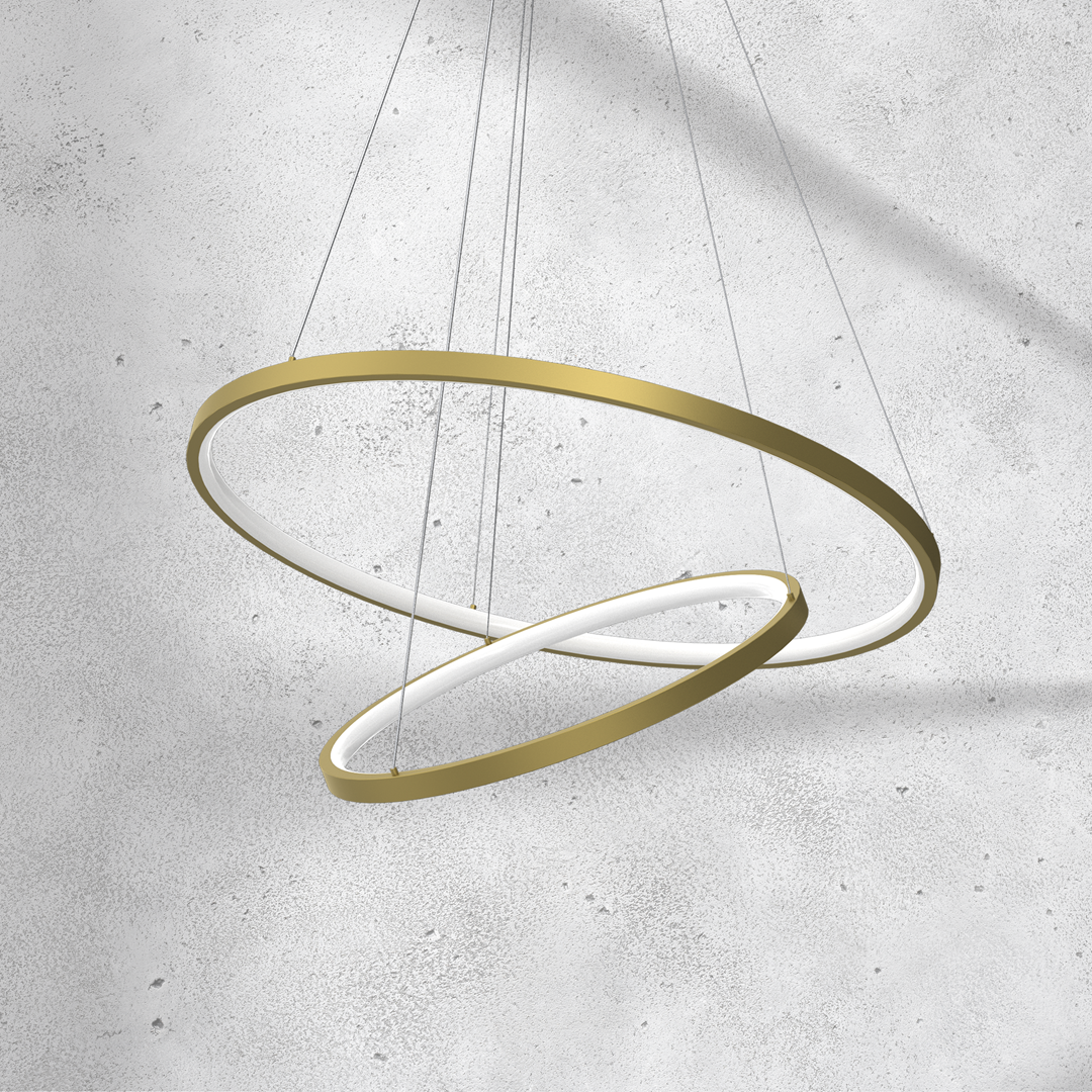 Lampa wisząca Hoop z dwoma okręgami, złota konstrukcja z białym podświetleniem LED, zawieszona na cienkich linkach. Okręgi mają różne średnice, co tworzy nowoczesny efekt. Tło w odcieniach szarości.