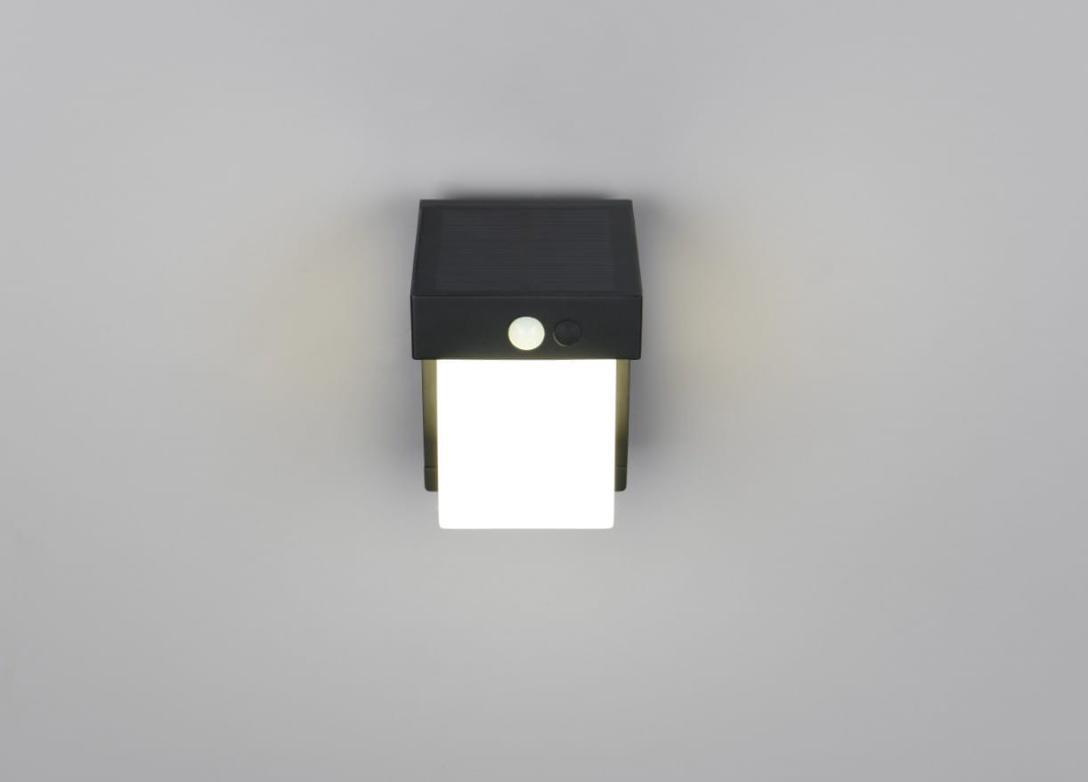 Kinkiet zewnętrzny Colombo Hybrid, czarny, z panelem solarnym, z białym kloszem LED o mocy 5,5W. Ujęcie frontalne, produkt zamontowany na ścianie, z widocznym przyciskiem i czujnikiem ruchu. Wodoodporność IP44, idealny do użytku na zewnątrz.