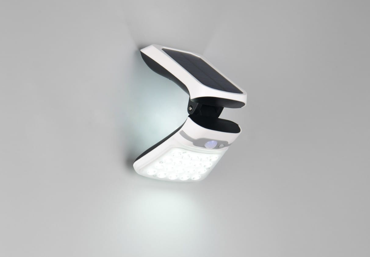 Kinkiet zewnętrzny solarno-LED w kolorze białym z czujnikiem ruchu i zmierzchu. Posiada prostokątną obudowę z widocznymi diodami LED, zamontowany na ścianie pod kątem, z panelem słonecznym na górze. Klasa szczelności IP44.