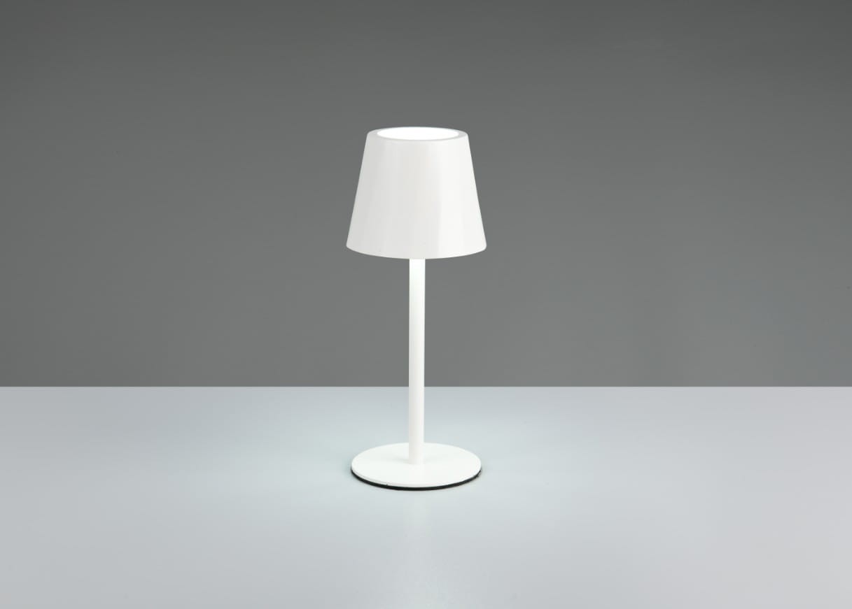 Lampa stołowa zewnętrzna Diaz w kolorze białym, z kloszem w kształcie stożka na prostym, okrągłym stelażu. Produkt stoi na płaskiej powierzchni, emitując delikatne światło LED. Idealna do użytku na tarasie lub w ogrodzie.