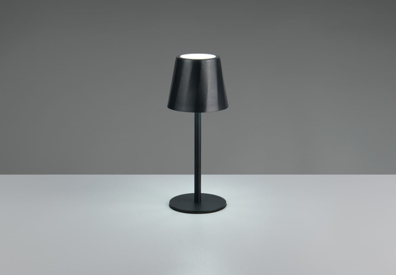 Czarna lampa stołowa zewnętrzna Diaz z kloszem w kształcie stożka, umieszczona na cienkiej, okrągłej podstawie. Posiada źródło światła LED o mocy 1,6 W. Ujęcie frontalne, produkt stoi na płaskiej, jasnej powierzchni. Tło w odcieniach szarości.