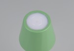 Zielona lampa stołowa zewnętrzna Diaz, z LED o mocy 1,6 W i regulacją temperatury barwowej (CCT). Ujęcie z góry, pokazujące zaokrąglony kształt i białą, okrągłą szybę na górze. Matowa powierzchnia, bez dodatkowych zdobień.