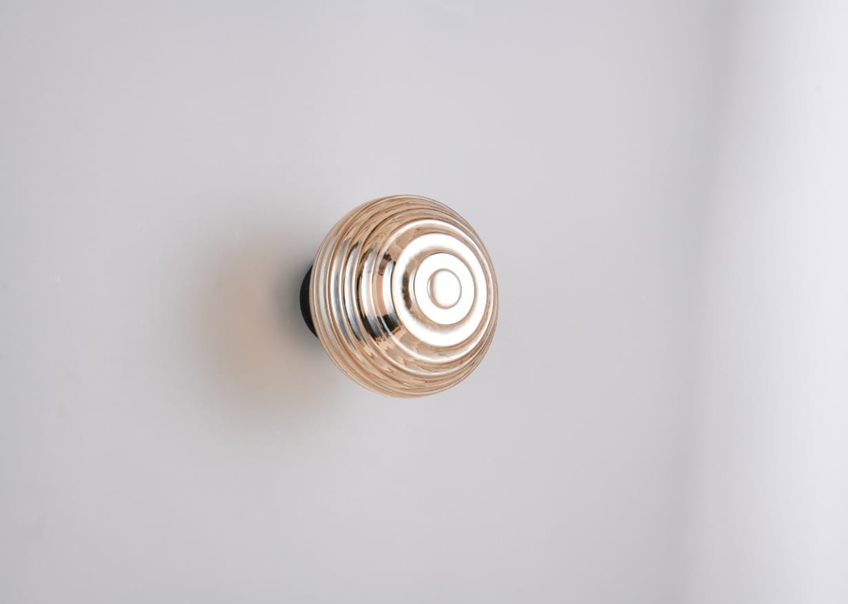 Kinkiet Earl w kolorze czarnym z bursztynową, okrągłą oprawą, o wypukłym kształcie z wyraźnym żłobieniem. Produkt zamontowany na ścianie, ukazany z góry. Wbudowane źródło światła LED o mocy 1,5W. Tło jasne, jednolite.