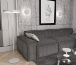Lampa stołowa Nemo w kolorze białym, z okrągłym kloszem i cienką, prostą podstawą. Ustawiona obok szarej kanapy w nowoczesnym wnętrzu. Widoczne elementy dekoracyjne w tle, w tym obraz i kinkiet.