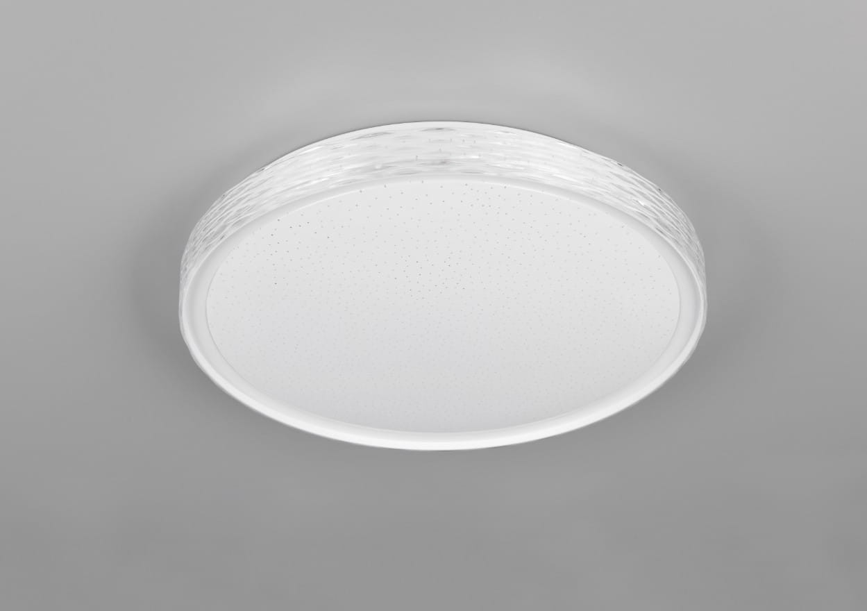 Plafon Varda w kolorze białym, okrągły, z fakturowaną ramką. Zainstalowane źródło światła LED o mocy 24W, możliwość regulacji temperatury barwowej. Widok z dołu, montowany na suficie, z pilotem do zdalnego sterowania.