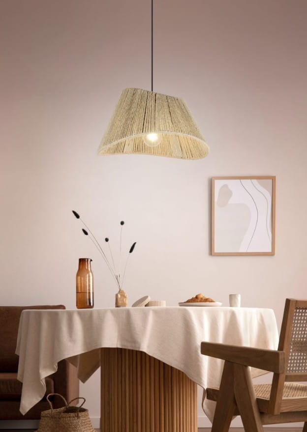 Lampa wisząca Valerie z kloszem w naturalnym kolorze, wykonana z tekstylnych włókien, zawieszona na cienkim czarnym przewodzie. Widoczna na tle minimalistycznej aranżacji stołu z białym obrusem i dekoracjami.