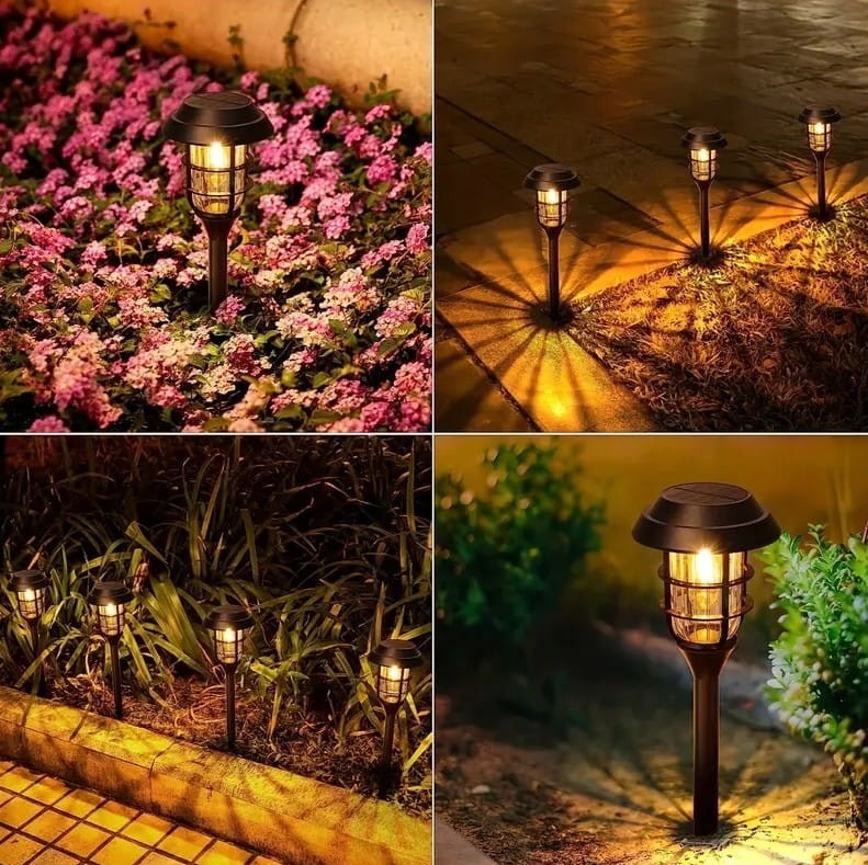 Latarnia solarna ogrodowa, czarna, wbijana, wysokość 45 cm, z lampą LED. Widoczna w różnych aranżacjach na tle kwiatów i trawy, emitująca ciepłe światło, tworząca dekoracyjne cienie. Zestaw 6 sztuk.