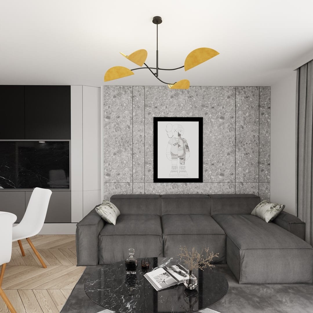Czarna lampa sufitowa Lotus z czterema oprawami E14, ozdobiona pomarańczowymi, stylizowanymi elementami. Zawieszona w nowoczesnym wnętrzu, na tle szarej ściany z grafiką, nad szarym sofą i okrągłym, czarnym stołem.
