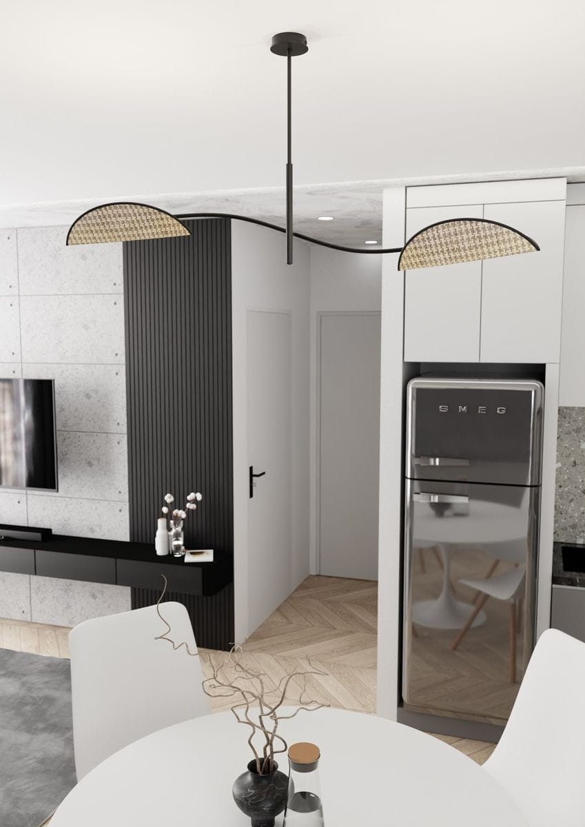 Lampa sufitowa Lotus z dwoma gniazdami E14, w kolorze czarnym z naturalnymi akcentami. Ujęcie z góry, lampa zwisająca na cienkim przewodzie, z okrągłym kloszem. W tle nowoczesne wnętrze z kuchnią oraz strefą wypoczynkową.