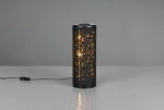 Czarna lampa stołowa Taco z LED 4W, cylindryczny kształt z perforowaną obudową, emitującą ciepłe światło przez otwory. Ujęcie frontalne, lampa stoi na stole, widoczny kabel z wyłącznikiem.