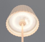 Lampa stojąca zewnętrzna Suarez w kolorze piaskowym, z kloszem o falistym kształcie i poświatą LED. Widok z góry na klosz i źródło światła. Klosz wykonany z przezroczystego materiału, podstawa prosta, elegancka.