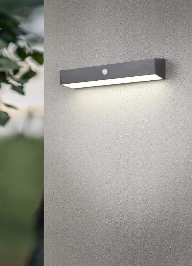 Kinkiet zewnętrzny Silves Hybrid w kolorze czarnym, montowany na ścianie, z wbudowanym czujnikiem. Oświetlenie LED 6W, IP44, prostokątny kształt, emituje jasne światło, umieszczony na gładkiej szarej powierzchni.