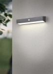 Kinkiet zewnętrzny Silves Hybrid w kolorze czarnym, montowany na ścianie, z wbudowanym czujnikiem. Oświetlenie LED 6W, IP44, prostokątny kształt, emituje jasne światło, umieszczony na gładkiej szarej powierzchni.