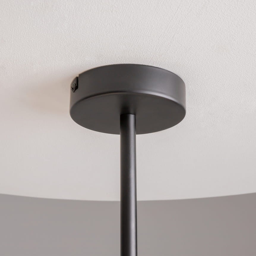 Czarna lampa wisząca Memory z 4 gniazdami E14, widok od dołu. Metalowa podsufitka z prostym, okrągłym kształtem, na długim, cienkim pręcie, zawieszona na białym suficie.