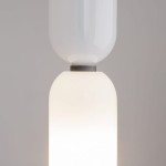 Lampa wisząca Memory z jednym gniazdem E14, w białym kolorze. Składa się z dwóch połączonych elementów: górnego, przezroczystego klosza oraz dolnego, matowego klosza o zaokrąglonym kształcie. Ujęcie z bliska, z przodu.
