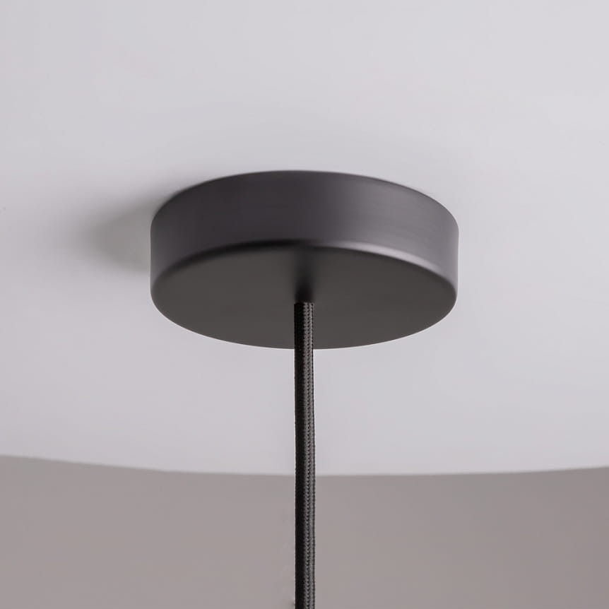 Lampa wisząca Memory z metalowym, okrągłym mocowaniem w kolorze czarnym, zawieszona na tekstylnym przewodzie. Widoczna konstrukcja z górnej perspektywy, przeznaczona do żarówki E14. Tło jasne, jednolite.