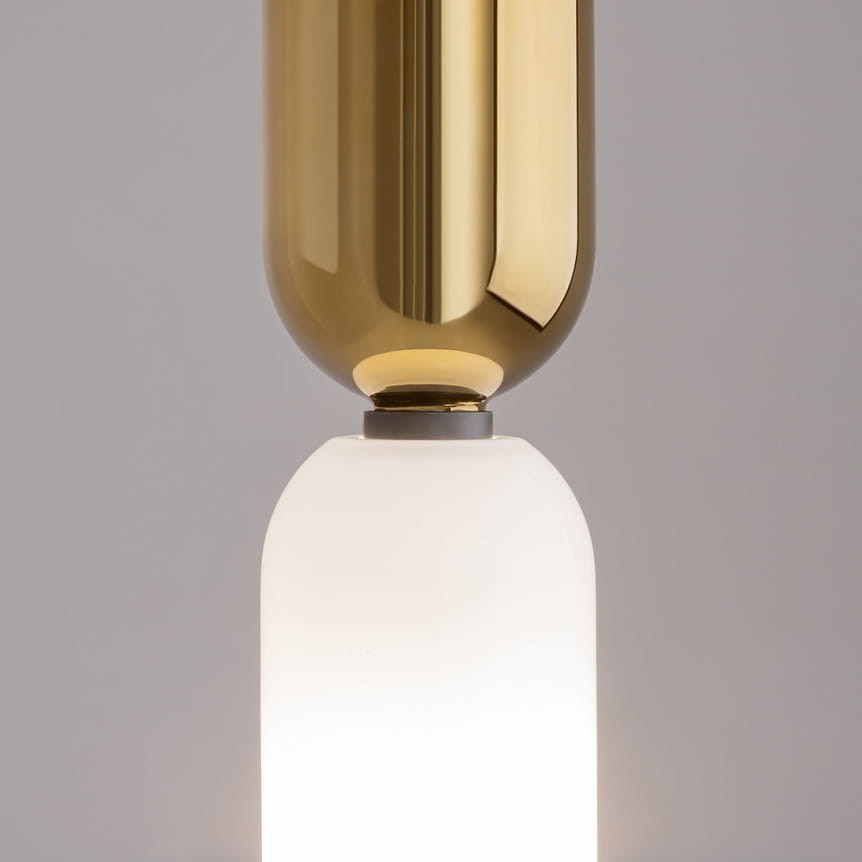 Lampa wisząca Memory 1xE14 w kolorze złotym, z górną, błyszczącą, okrągłą osłoną oraz dolną, matową, szklaną częścią w kształcie walca. Ujęcie zbliżeniowe, ukazujące detale konstrukcji i połączenie materiałów. Tło w jednolitym, neutralnym kolorze.