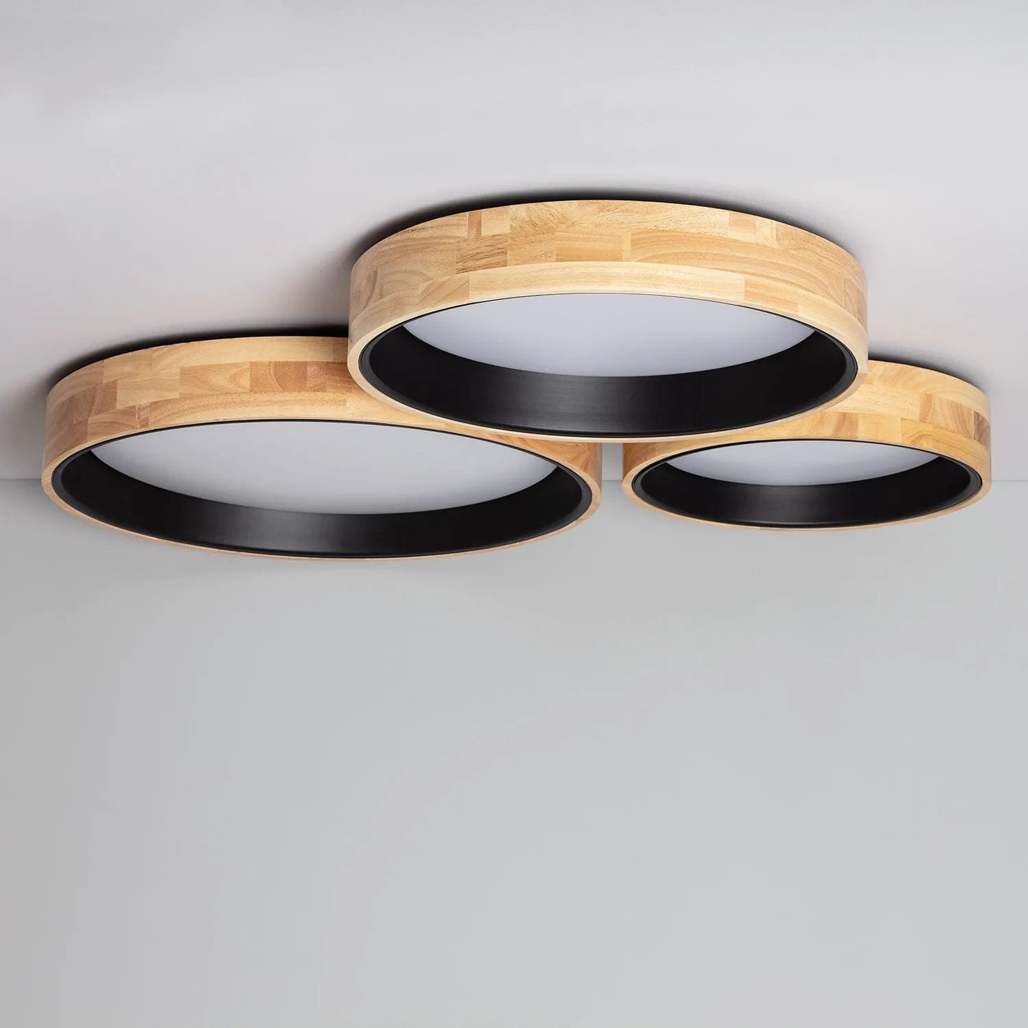 Plafon Vero D60 z trzema okrągłymi oprawami, wykonany z drewna w kolorze naturalnym i czarnym. Zainstalowany na suficie, z białym kloszem LED o mocy 31W, widoczny z góry z eleganckim, minimalistycznym designem.