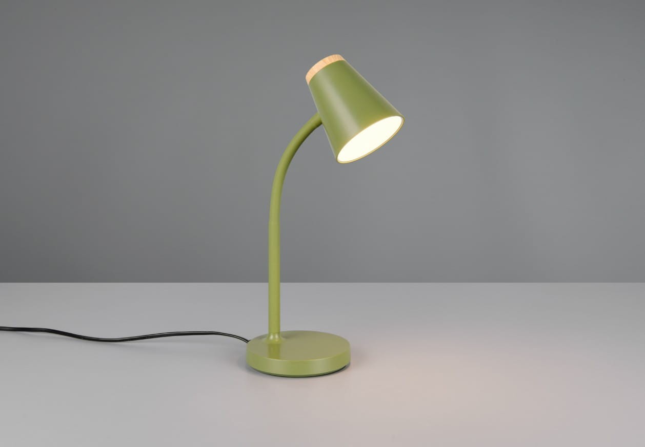 Lampa biurkowa Pongo, zielona, z metalowym kloszem w kształcie stożka i drewnianym akcentem u góry. Ustawiona na okrągłej podstawie, z wygiętym ramieniem. Na stole, włączona, emitująca ciepłe światło. Kabel zasilający widoczny z boku.