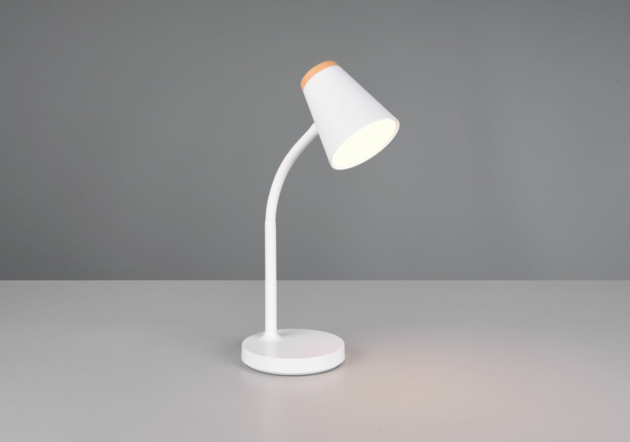 Biała lampa biurkowa Pongo z lampą LED 4,5W, posiadająca zaokrągloną podstawę i elastyczny, łukowaty uchwyt. Oświetlenie w kloszu o stożkowym kształcie z drewnianym akcentem na górze, ustawiona na gładkiej powierzchni.