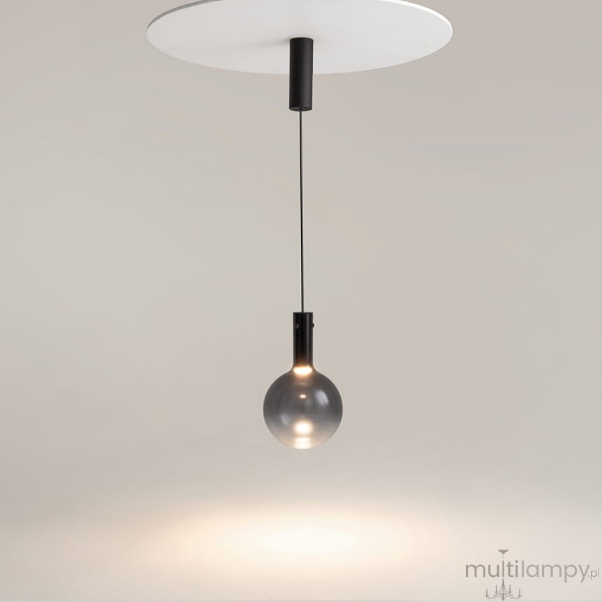 Lampa wisząca Nebula D20 z czarnym wykończeniem, z pojedynczym źródłem światła LED 4W. Okrągła, szklana kula zawieszona na cienkim przewodzie, montowana do białej podsufitki. Prosta forma w nowoczesnym stylu.