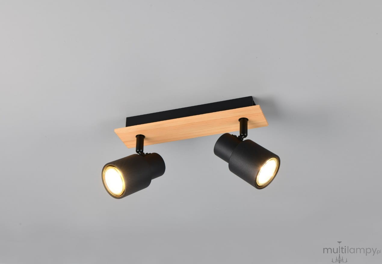 Lampa sufitowa Pierre z dwoma reflektorami GU10, czarna z jasnym drewnem. Ujęcie z góry, montowana na prostokątnej podstawie z drewna. Reflektory skierowane w różne strony, z metalicznymi kloszami. Tło szare.
