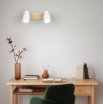 Lampa sufitowa Pierre w kolorze białym z jasnego drewna, z dwoma punktami świetlnymi GU10. Ujęcie frontalne, zamontowana na ścianie nad biurkiem, w tle widać dekoracje i akcesoria biurowe.