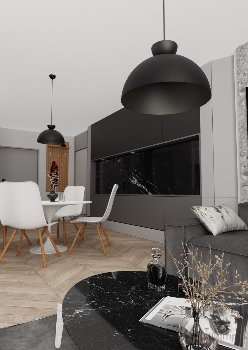 Czarna lampa wisząca Lunaro L z jednym źródłem światła GX53, w stylowym, zaokrąglonym kształcie. Zawieszona nad okrągłym stołem w jadalni, na tle ciemnych szafek kuchennych i jasnych krzeseł. Eleganckie, nowoczesne wykończenie.