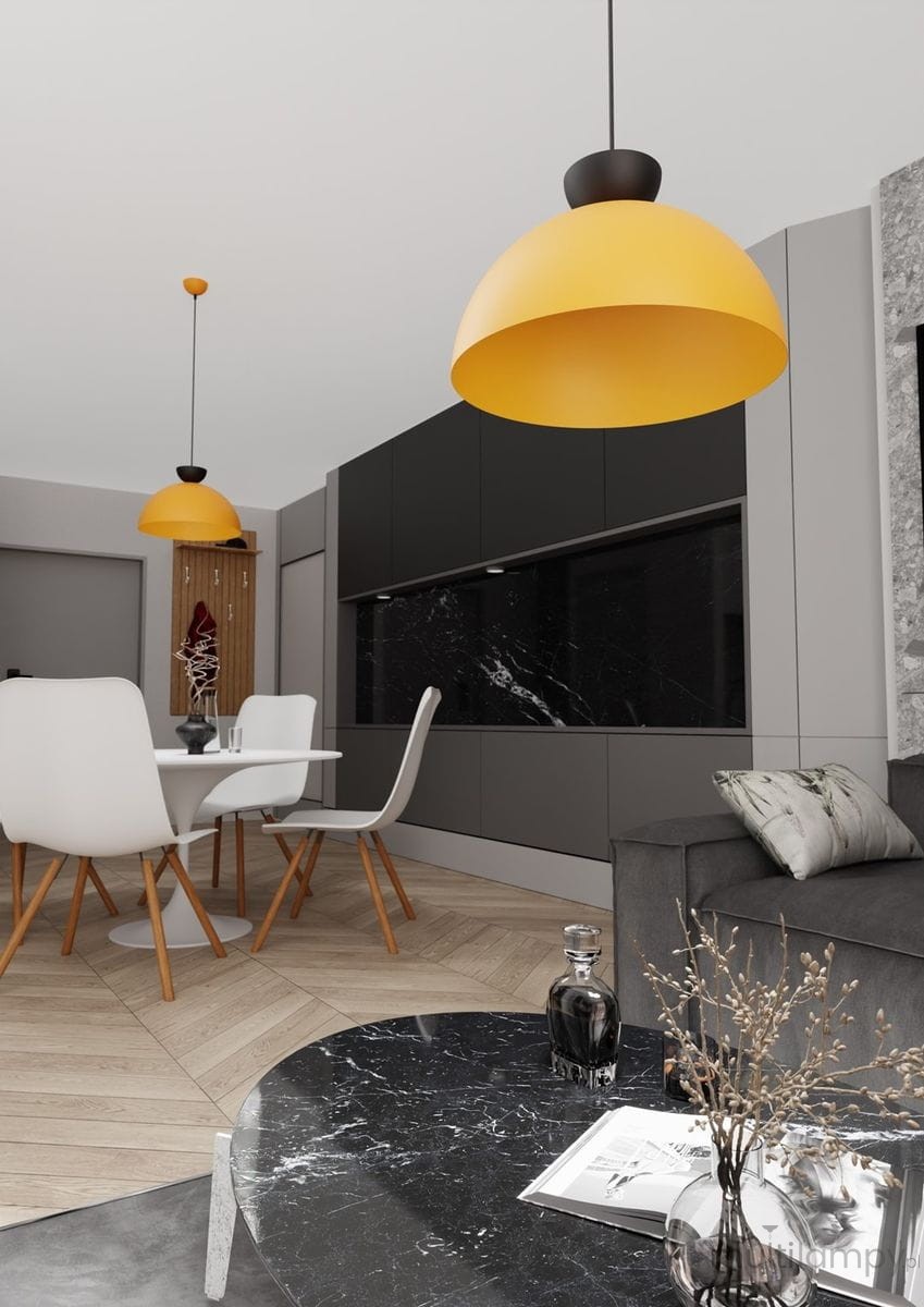 Lampa wisząca Lunaro L w kolorze pomarańczowym, z kloszem w kształcie półkuli, zawieszona na cienkim kablu. W tle nowoczesna kuchnia z czarnymi meblami, białym stołem i krzesłami. Lampa podkreśla styl wnętrza.