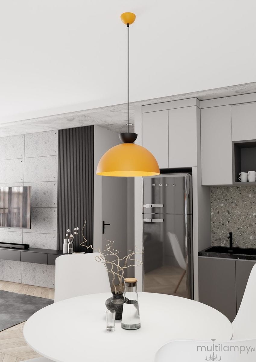Pomarańczowa lampa wisząca Lunaro L z oprawą GX53, zawieszona na czarnym przewodzie, w kuchni na tle szarych mebli i metalowej lodówki. Lampa ma półkolisty kształt, a jej górna część jest czarna, co kontrastuje z jasnym kloszem.