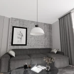 Lampa wisząca Lunaro L w kolorze białym z czarnym detalem, zawieszona nad szarym narożnikiem w nowoczesnym wnętrzu. Tło stanowi szara ściana z teksturą oraz obraz w czarnej ramie. Na stole widoczne książki i dekoracja w wazonie.