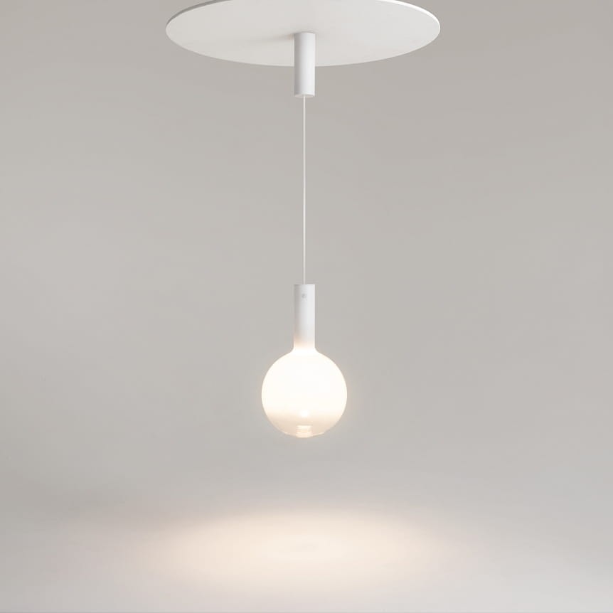 Lampa wisząca Nebula D25 w kolorze białym, z pojedynczym źródłem światła LED o mocy 6W. Okrągła, przezroczysta kula z opalizującego szkła zawieszona na cienkim kablu z metalowym uchwytem. Prosty, nowoczesny design na jasnym tle.