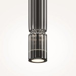 Lampa wisząca LED Ordo H38 o mocy 8W, w kolorze czarnym z dymionym kloszem. Kształt cylindryczny z żłobieniami, zamontowana w pionie. Emituje ciepłe światło, idealna do nowoczesnych wnętrz. Tło jasne, podkreślające detal lampy.
