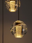 Lampa wisząca Cuyo z pięcioma źródłami LED o mocy 16W, złota, z okrągłymi kloszami z przezroczystego materiału z bąbelkami powietrza oraz dekoracyjną siatką wewnętrzną. Ujęcie z bliska, prezentujące detale i fakturę.