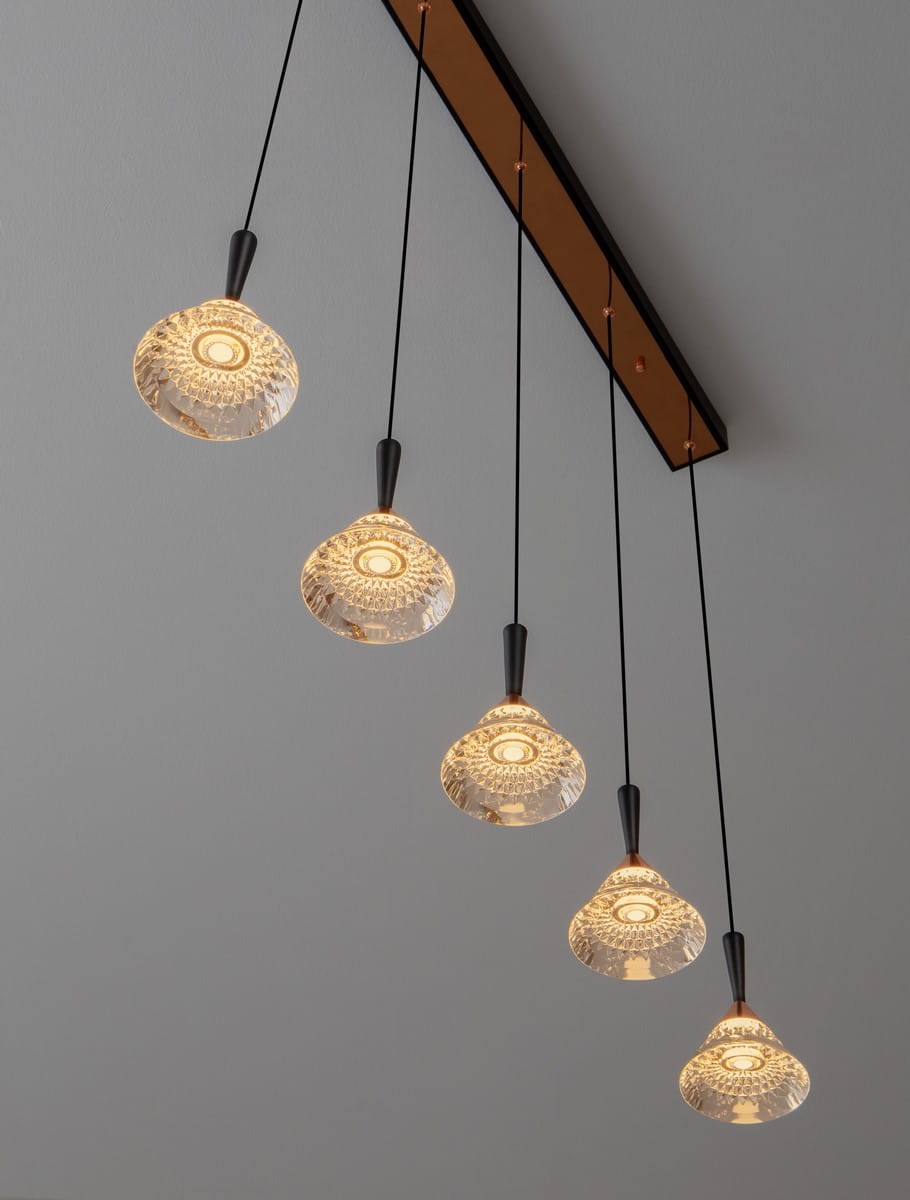 Lampa wisząca Guay z pięcioma kloszami LED, czarna ze złotymi akcentami. Klosze mają przeszkloną strukturę, zwisają na cienkich linkach z metalowego mocowania. Oświetlenie w ciepłym odcieniu, idealne do nowoczesnych wnętrz.